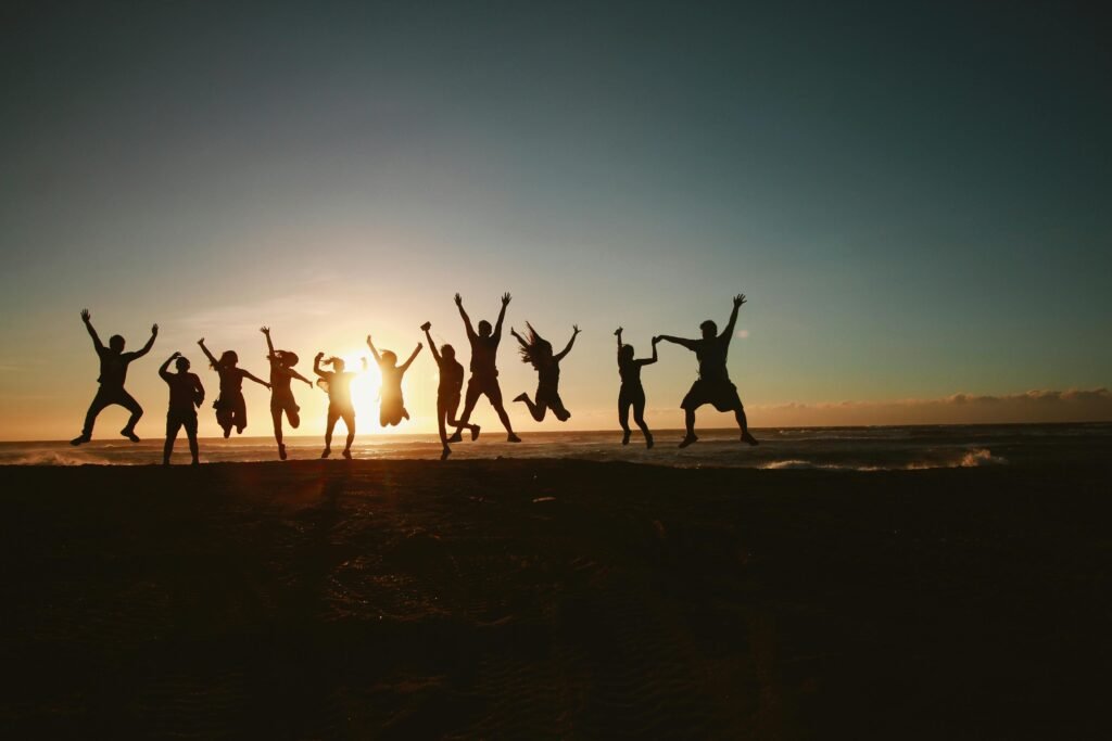 pexels photo 1000445 1000445 Silhouette of a group of friends jumping on a beach at sunset, expressing joy and freedom.
